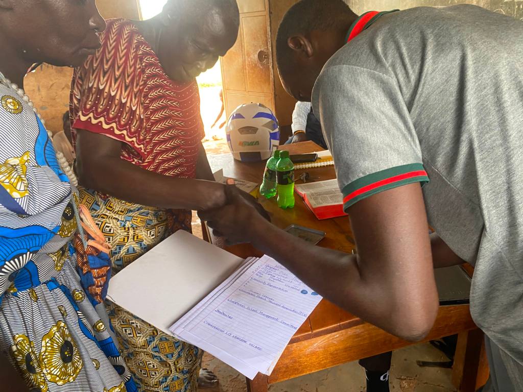 Korobar community and Amigos representatives completing the July 9, 2026 land handover paperwork at a table.